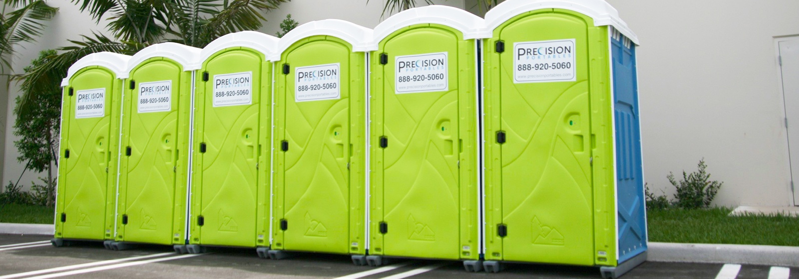 Portable Restrooms by Precision Portables lined up on the side of a building in South Florida